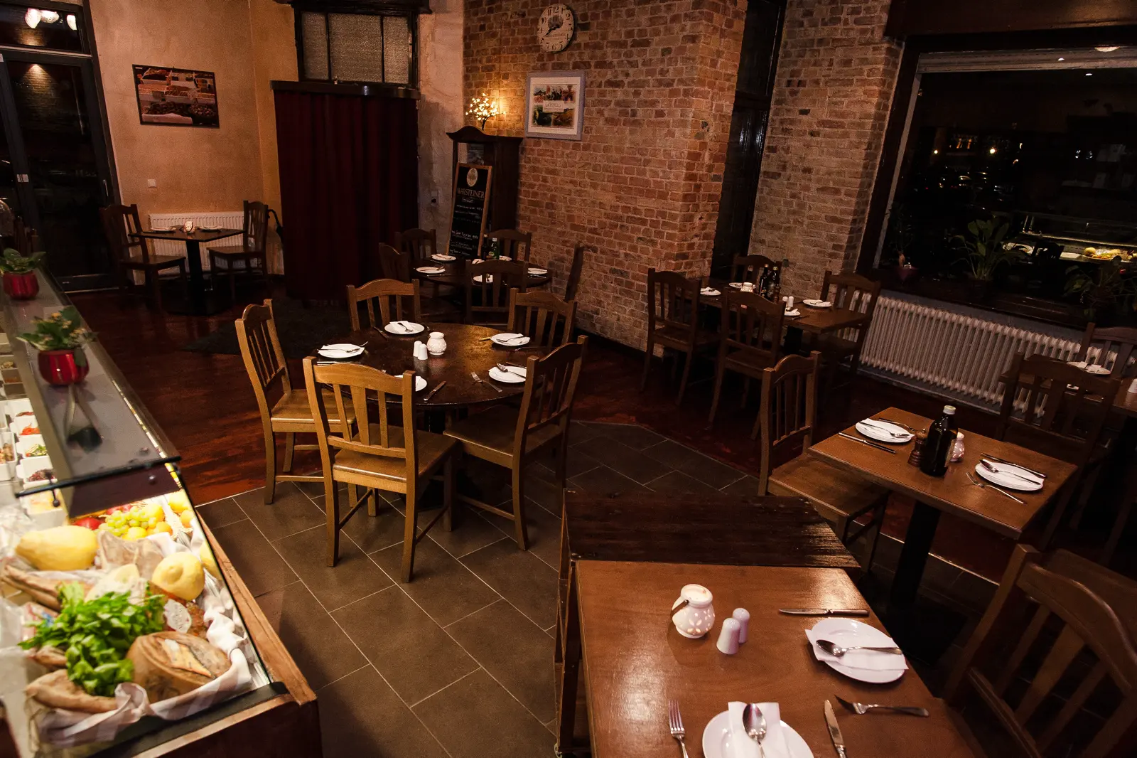 Trattoria Lauretta Berlin — Raumperspektive mit Tischen und klassischer Dekoration